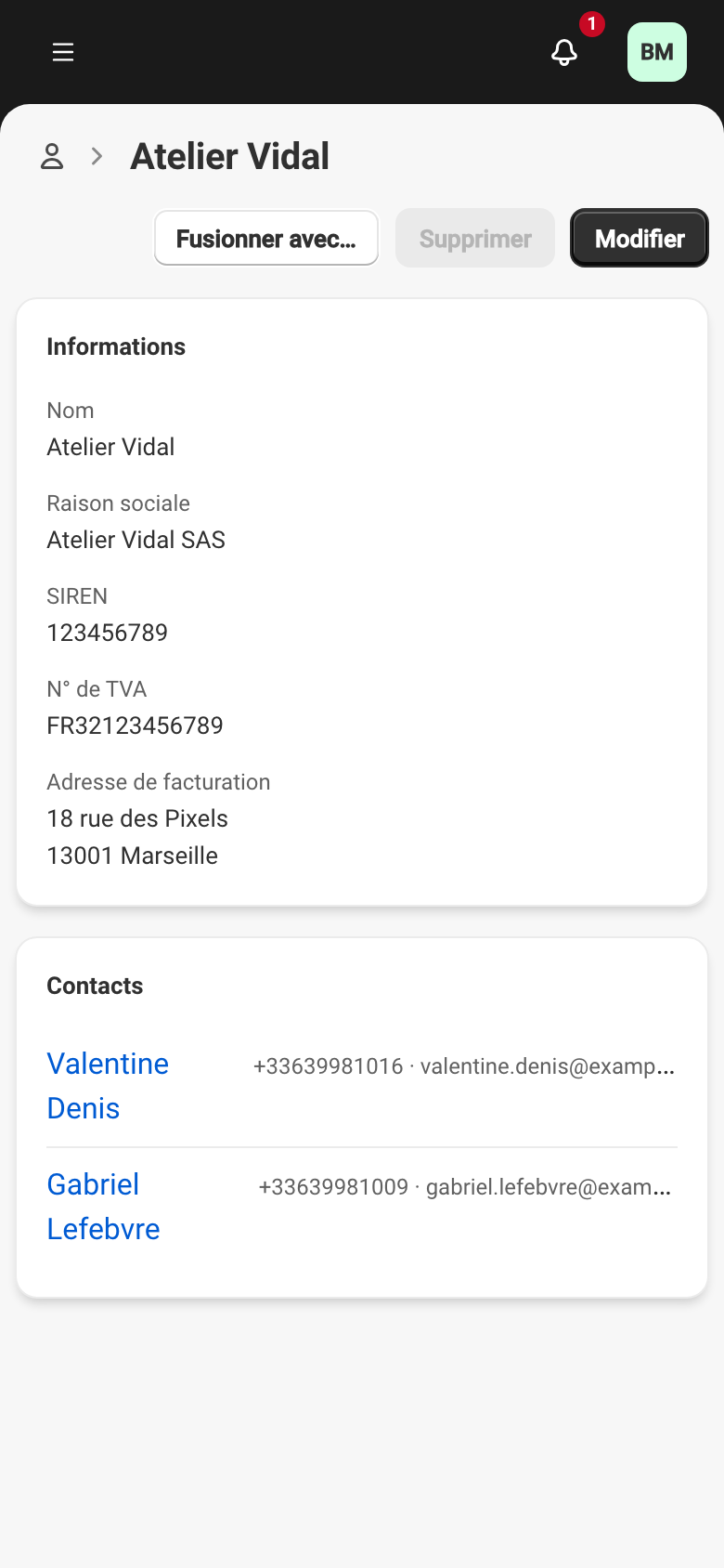 La fiche de l'entreprise Atelier Vidal : la carte Informations avec le nom, la raison sociale, le SIREN, le numéro de TVA et l'adresse de facturation, puis la carte Contacts listant Valentine Denis et Gabriel Lefebvre avec leur téléphone et leur e-mail. En haut, Fusionner avec…, Supprimer grisé, et Modifier.